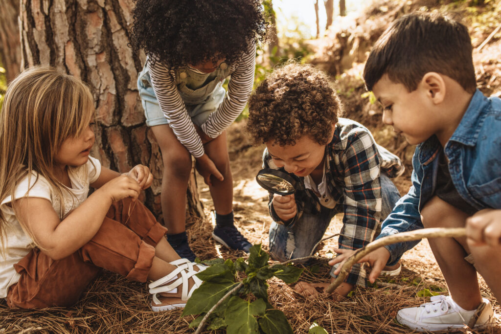 Kids exploring in forest with a magnifying glass